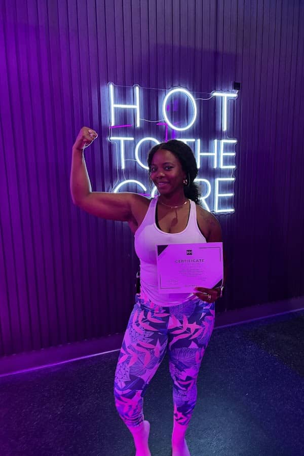Member flexing under the Hot to the Core neon sign in the HILI Lake Nona infrared hot mat room