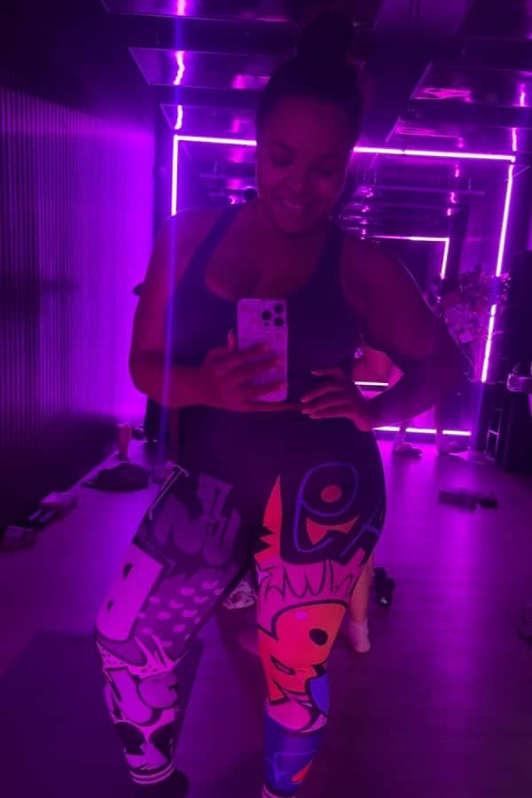 Member in the neon-lit infrared hot mat pilates room at HILI Fitness Waterford Lakes