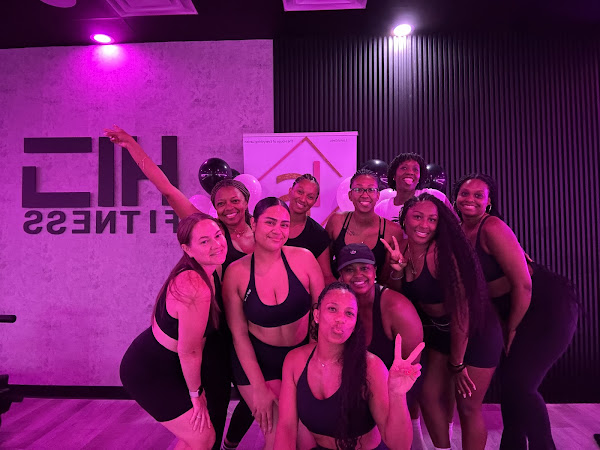 Members posing in front of the HILI Fitness logo wall at a Lake Nona pilates studio event