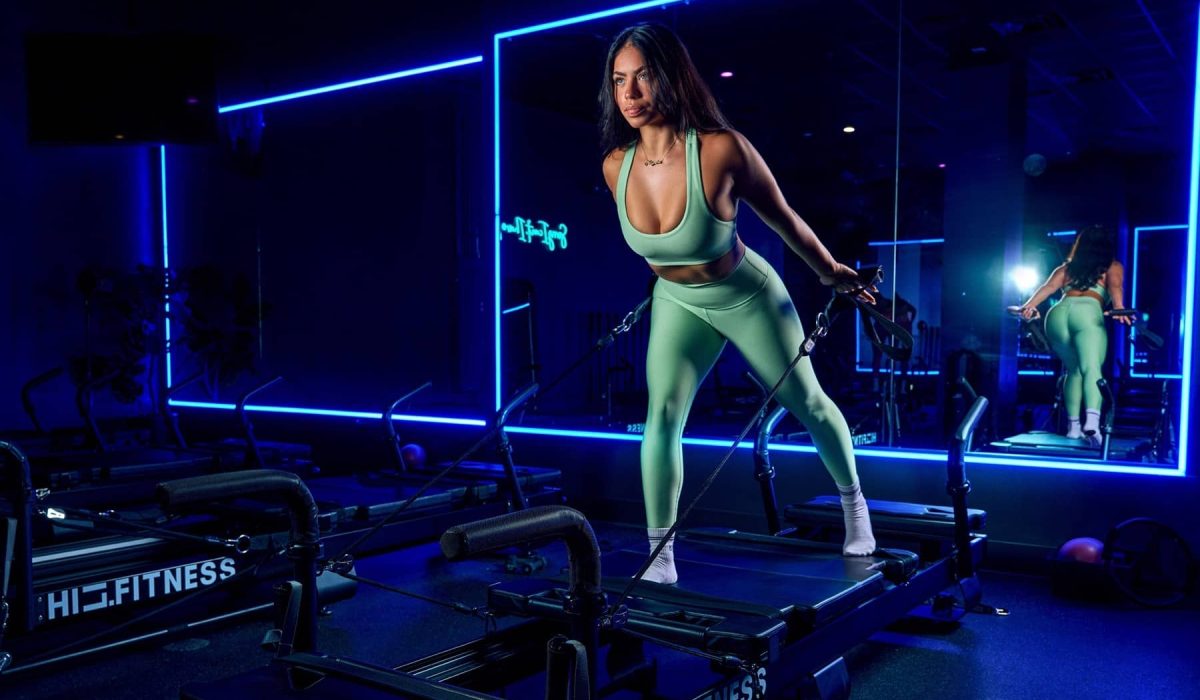 Member balancing on an XFormer pilates machine in the blue-lit strength room at HILI Fitness